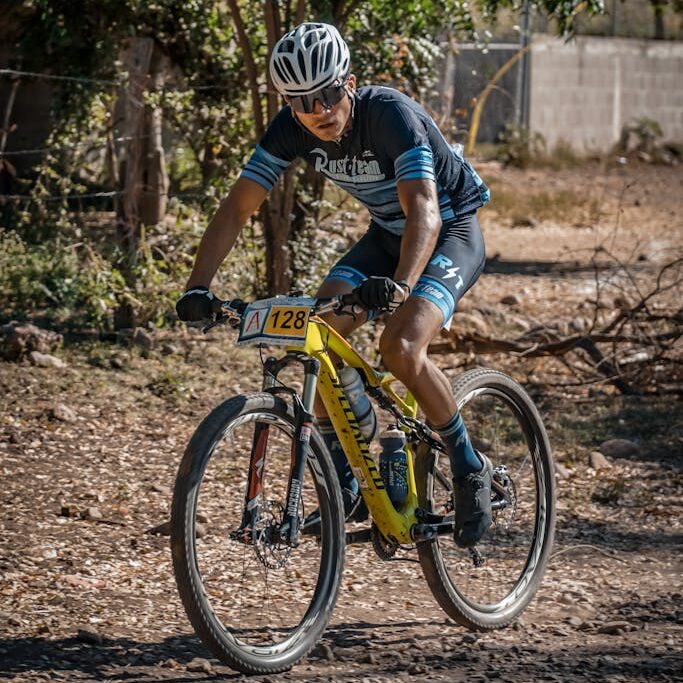 Foto por Jose Ricardo Barraza Morachis Cyclist riding through rugged terrain in a mountain biking competition under a sunny sky.